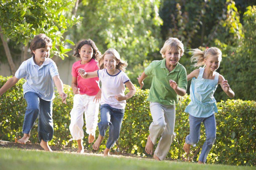 A group of children running in the grass.