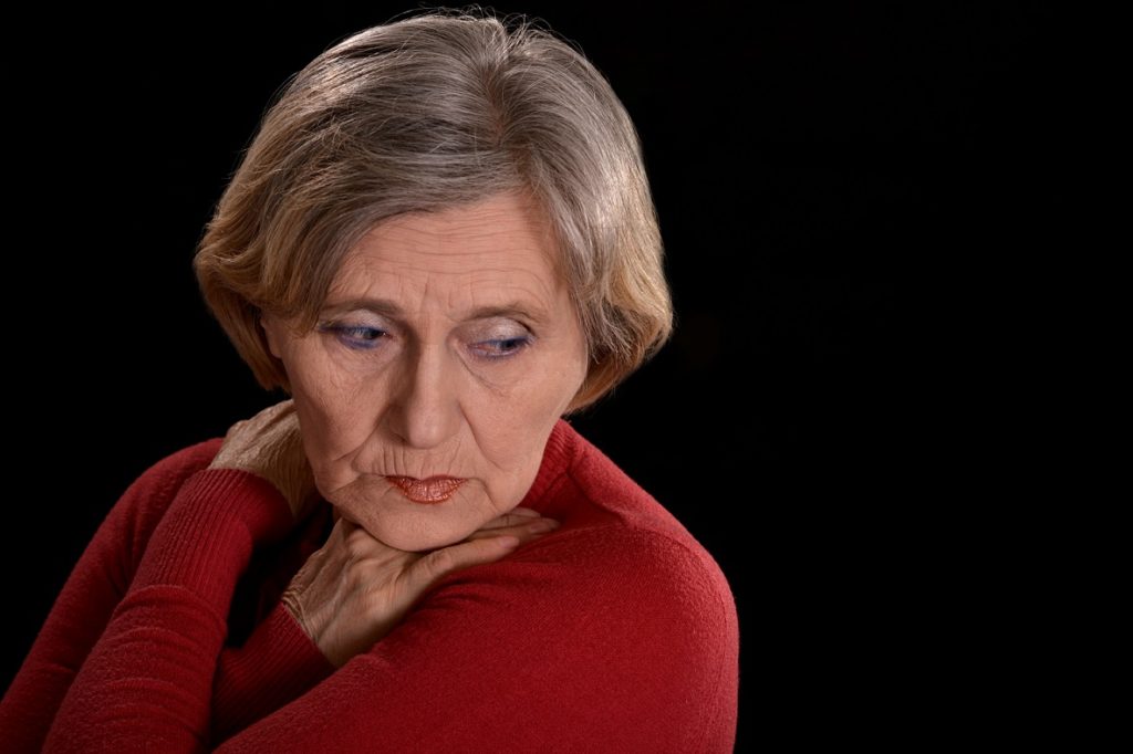 A woman in red is holding her chin.