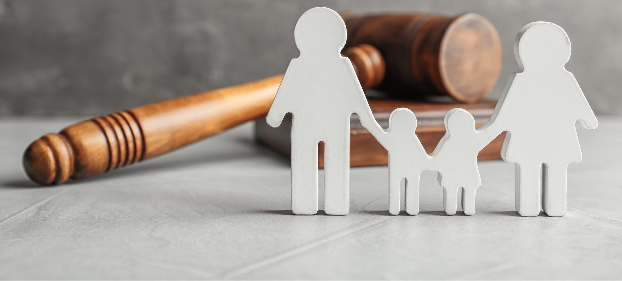 A wooden gavel and two paper people on the floor.