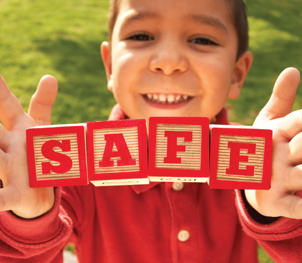 A boy holding blocks that spell out " safe ".